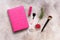 Women`s workspace. Pink notepad and female accessories on a beige rustic background. Top view, flat lay