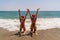 Women Santa hats ocean play. Seaside, beach daytime, enjoying beach fun. Two women in red swimsuits and Santa hats are