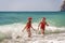 Women Santa hats ocean play. Seaside, beach daytime, enjoying beach fun. Two women in red swimsuits and Santa hats are