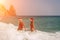 Women Santa hats ocean play. Seaside, beach daytime, enjoying beach fun. Two women in red swimsuits and Santa hats are