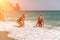 Women Santa hats ocean play. Seaside, beach daytime, enjoying beach fun. Two women in red swimsuits and Santa hats are