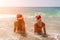 Women Santa hats ocean play. Seaside, beach daytime, enjoying beach fun. Two women in red swimsuits and Santa hats are