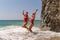 Women Santa hats ocean play. Seaside, beach daytime, enjoying beach fun. Two women in red swimsuits and Santa hats are