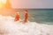 Women Santa hats ocean play. Seaside, beach daytime, enjoying beach fun. Two women in red swimsuits and Santa hats are