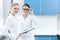 Women scientists in white coats and glasses smiling at camera in lab