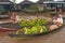 women selling fruit, at a floating market, offering fresh bananas from their boats, to buyers, in morning.