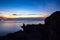 Women siting on a ledge of a mountain, enjoying the beautiful sunset over a wide river valley