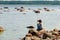 Women sitting on stone near sea and taking photo by phone camera. Stone and sea landscape.