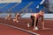 Women sprinters at starting position ready for race on racetrack.