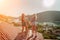 women standing on rooftop, enjoys town view and sea mountains. Peaceful rooftop relaxation. Below her, there is a town