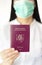 A women with a surgical mask holding Lithuanian passport