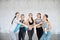 Women team united hands in gym, loft studio. Group of young sporty girls with yoga mats standing at wall