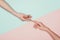 Women touching fingers on halved pink and turquoise surface