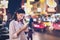 Women use smartphone at night on city shopping street, and use the map application in navigation.