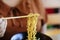 Women use wooden chopsticks to curl noodles for lunch