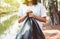 Women volunteer holding black color garbage bag at outdoor,Dispose waste management and plastic recycle concept