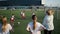 Women watch children football play on soccer field