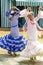 Women wearing traditional Sevillana dresses and dancing a Sevillana at the Seville April Fair