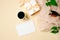 Women workspace with paper card, coffee cup, green leaves, gift box, glasses on beige background. Feminine desktop. Wedding