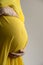 Women in yellow dress holding her pregnant abdomen