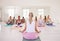 Women with yoga instructor meditating in lotus pose with mudra hand gesture during fitness class in a studio. Back of