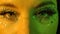 Womens eyes with sparkles and rhinestones, illuminated with yellow and green neon light, look straight ahead. Close up