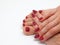 Womens fingers lie on the foot, varnish is visible on the fingers and toes, shiny red varnish