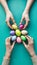 womens hands arranging vibrant Easter eggs, greeting card with space for text Top view