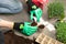 Womens hands in green gloves planting seeds at home in fertile black earth. In background freshly grown sprouts. Spring and