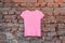 Womens pink t-shirt hanging on a hanger on a brick wall in the street