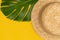 Womens summer straw hat on yellow background with monstera leaf, top view, flat copy space. Summer vacation concept, one