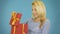 Wondered cute blonde young woman opening red gift box over blue background