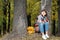 Wonderful autumnal view. Charming young happy smiling woman sitting on the grass in a park, take notes in notebook.