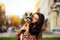 Wonderful closeup photo of a happy dog-owner female hugging her little puppy - yorkie. City street on the blurred background