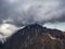 Wonderful dramatic landscape with big snowy mountain peaks above low clouds. Atmospheric large snow mountain tops in cloudy sky