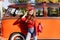 Wonderful european girl with trendy leather backpack standing in confident pose near orange bus. Refined french woman in