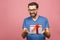 Wonderful gift! Adorable photo of attractive man with beautiful smile holding his birthday present box isolated over pink