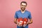 Wonderful gift! Adorable photo of attractive man with beautiful smile holding his birthday present boxes isolated over pink