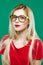 Wonderful Portrait of Cute Smart Girl in Eyeglasses and Red Top. Studio Short of Beautiful Blonde on Green Background.