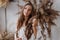 Wonderful portrait of a girl in a white boho dress against a background of dried flowers, looks like goddess