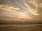 Wonderful relaxation on the shores of the Indian ocean, looking at the waves, colored clouds that reflect on the wet sand.