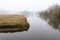 Wonderful rural landscape. Quiet river on a foggy spring morning. Medium and tall trees are shrouded in fog.