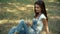 Wonderful smiling girl sits on the grass on the street listening to music