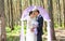 Wonderful stylish rich happy bride and groom standing at a wedding ceremony in green garden near purple arch with