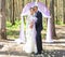 Wonderful stylish rich happy bride and groom standing at a wedding ceremony in green garden near purple arch with