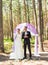 Wonderful stylish rich happy bride and groom standing at a wedding ceremony in green garden near purple arch with