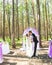 Wonderful stylish rich happy bride and groom standing at a wedding ceremony in green garden near purple arch with