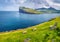 Wonderful summer view of Eidi village. Gloomy morning scene of Eysturoy island with Eidiskollur cliffs on background. Nice landsca