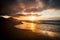 Wonderful timeless sunset at the beach with dramatic clouds and waves - mountains in background and wild scenic place - golden and