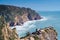 Wonderful view of blue lagoon, rocky beach seashore coastline, stormy waves surrounded by mountains cliffs on windy day.